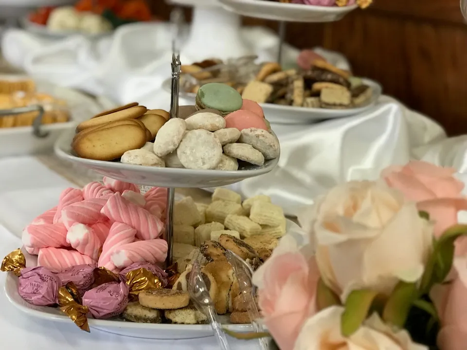 Platters of cookies and sweets beside blush roses