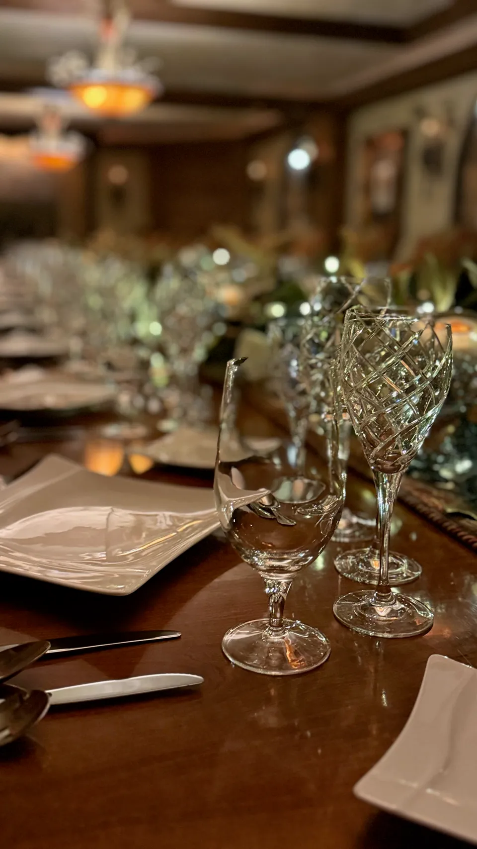 Crystal stemware and square plates along a formal dinner table