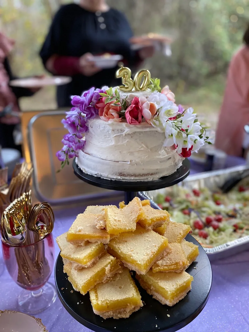 Floral-topped thirtieth birthday cake beside a dessert spread