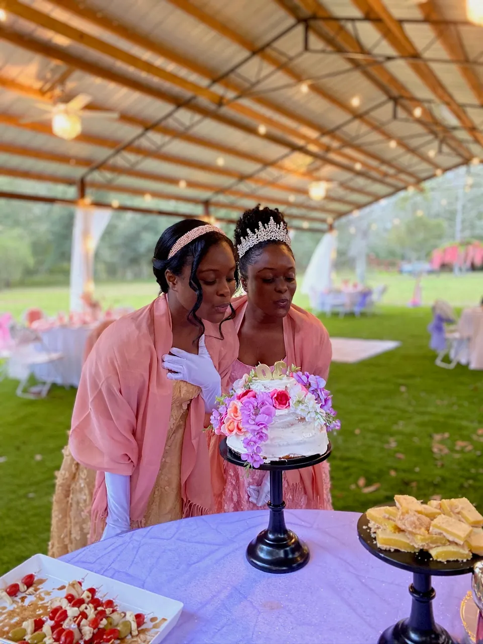 Two guests admiring a floral cake under a garden pavilion